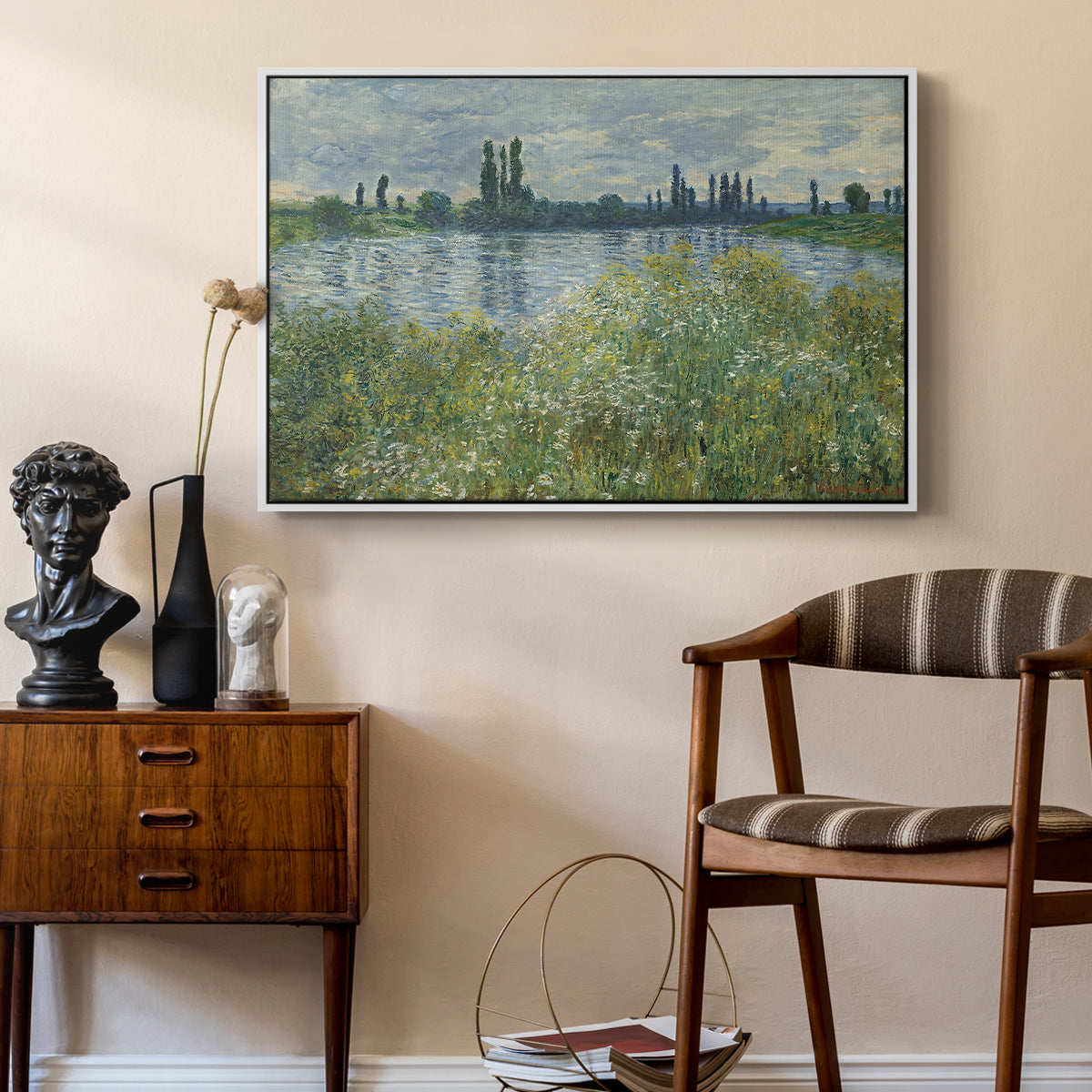 Banks of the Seine, Vétheuil, 1880 by Claude Monet as a white floater framed canvas featuring a tranquil riverside scene with houses and vegetation, styled above a mid-century console in a contemporary living area.