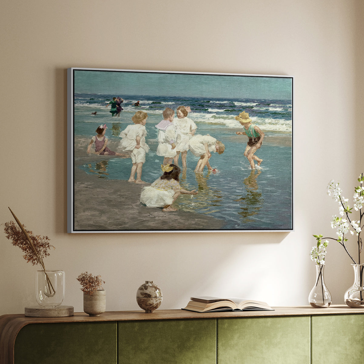 White floater framed canvas of A Holiday, c. 1915 by Edward Henry Potthast, featuring a beach scene with figures bathing and standing in waves under bright sky above a sideboard in a softly lit hallway.