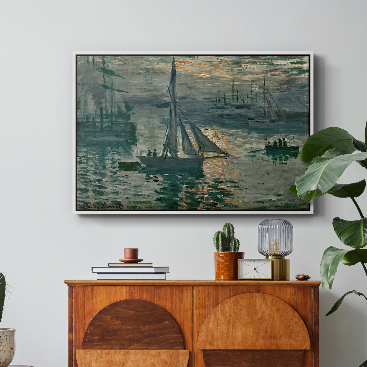 Sunrise (Marine), 1873 by Claude Monet in a white floater framed canvas featuring a hazy sunrise over harbor with boats silhouetted in soft morning light, displayed above a wood console cabinet.