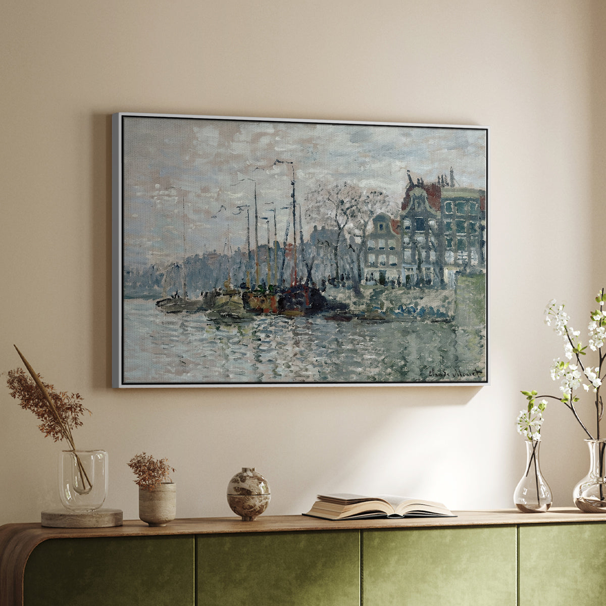 White floater framed canvas of View of the Prins Hendrikkade and Kromme Waal in Amsterdam, 1874 by Claude Monet, featuring an impressionist cityscape of canal with ships and architecture above a sideboard in a softly lit hallway.