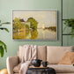 White floater framed canvas featuring a peaceful village scene with houses bordering water, displayed above a sofa in a modern living room.