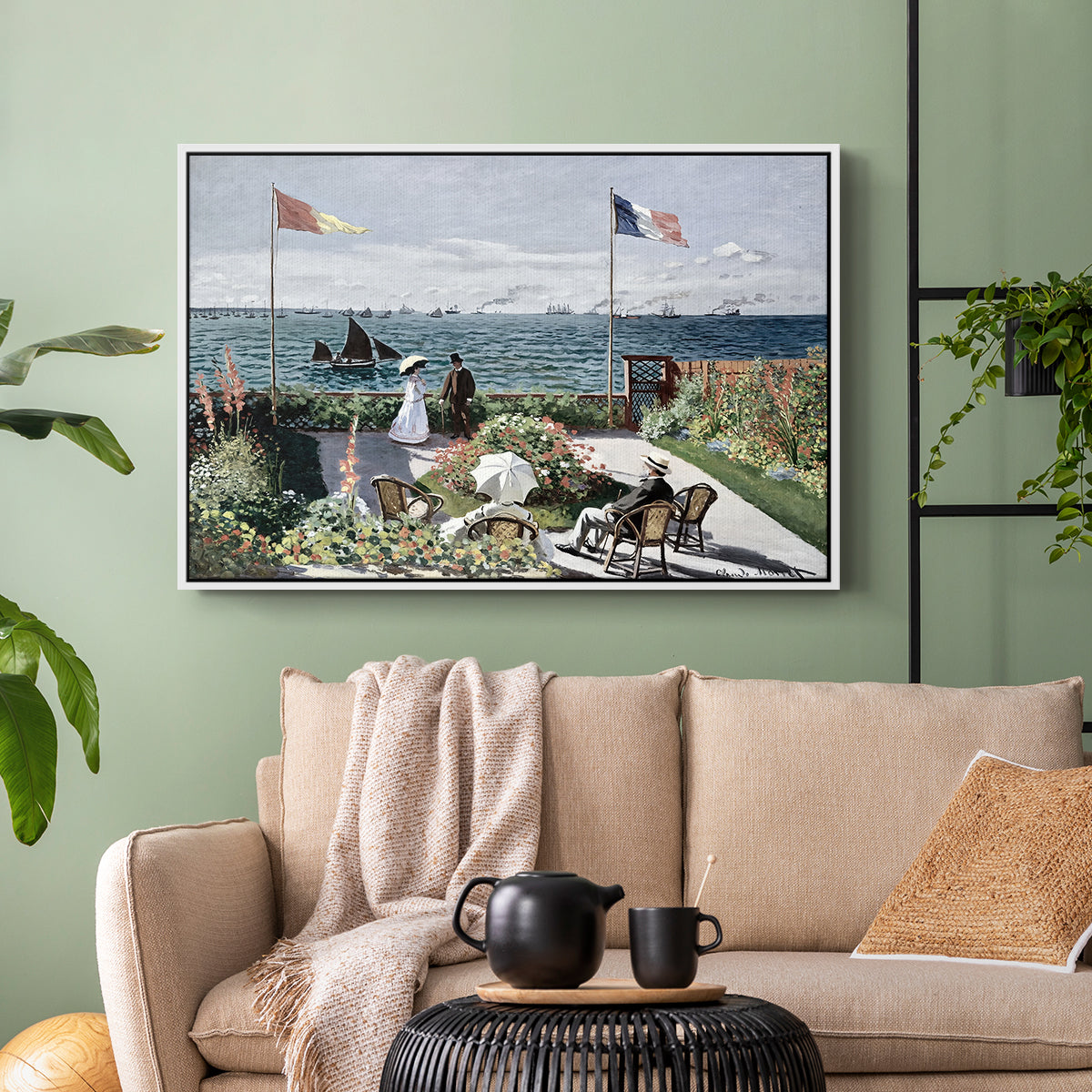 White floater framed canvas featuring a landscaped terrace with figures and flags near shoreline, displayed above a sofa in a modern living room.
