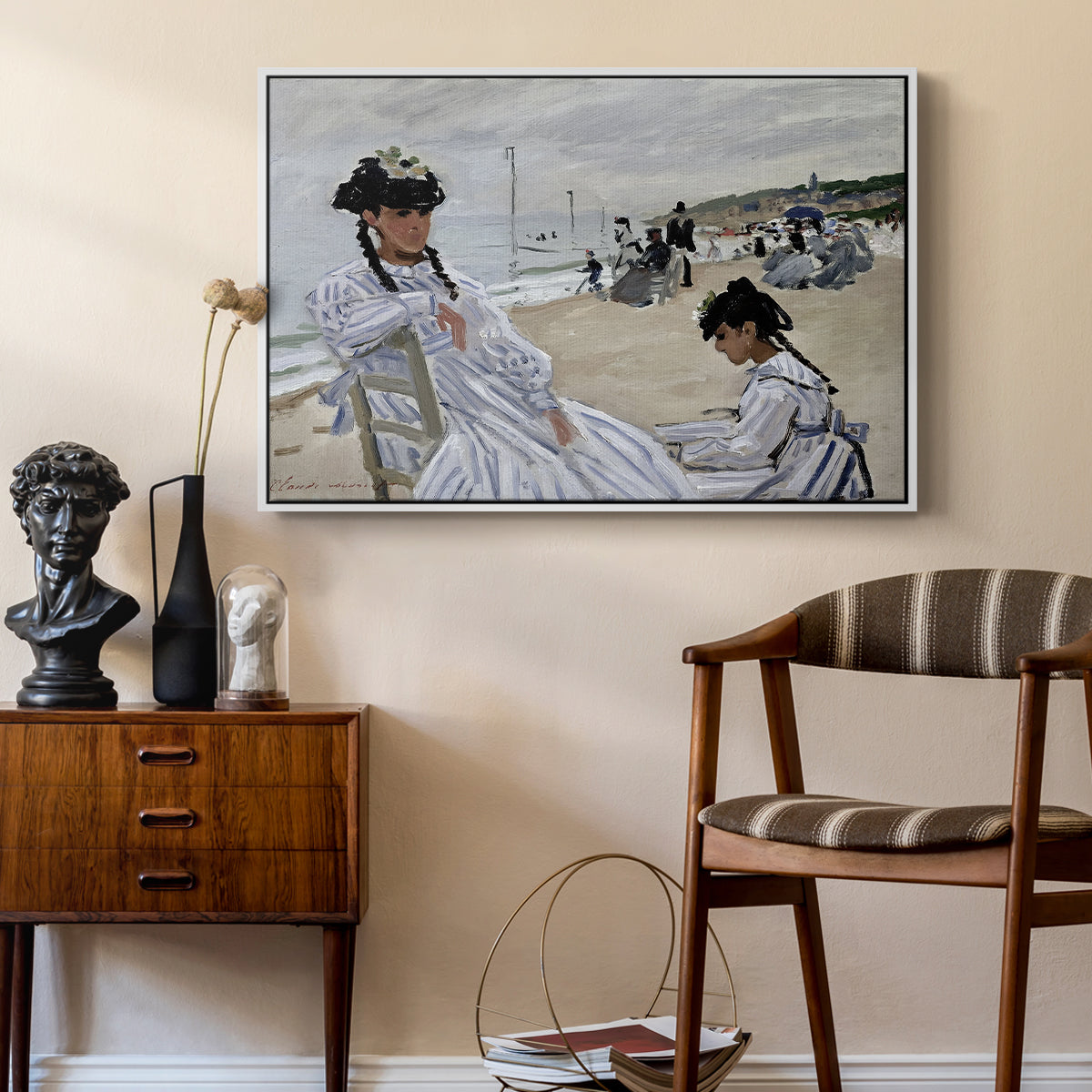 On the Beach at Trouville, 1870 by Claude Monet as a white floater framed canvas featuring a beach setting with people relaxing under umbrellas, styled above a mid-century console in a contemporary living area.