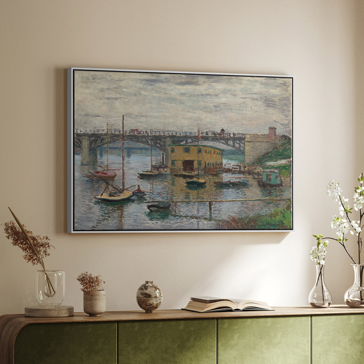 White floater framed canvas of Bridge at Argenteuil on a Gray Day, c. 1876 by Claude Monet, featuring an impressionist riverscape with overcast atmosphere and soft tones above a sideboard in a softly lit hallway.