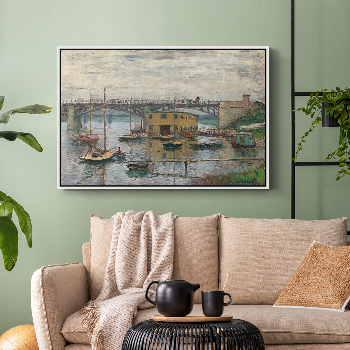White floater framed canvas featuring a subdued urban landscape with structure spanning river, displayed above a sofa in a modern living room.