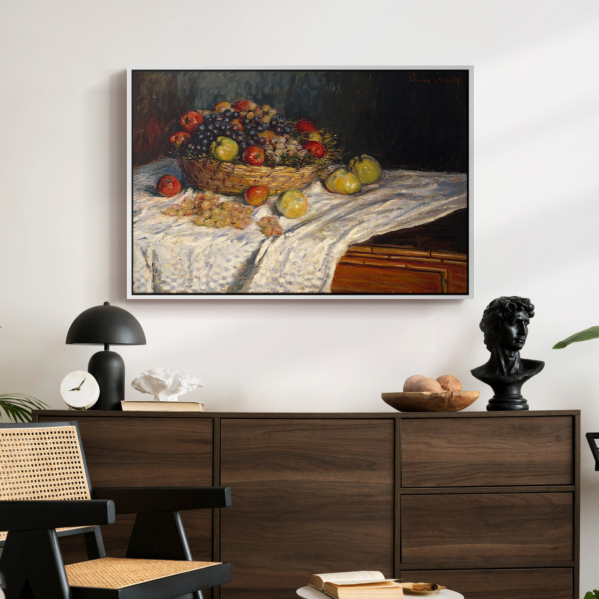Still Life with Apples and Grapes, 1880 by Claude Monet displayed in a white floater framed canvas above a dark wood credenza in an entryway.