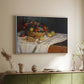 White floater framed canvas of Still Life with Apples and Grapes, 1880 by Claude Monet, featuring an impressionist still life of fruit placed on cloth-covered surface above a sideboard in a softly lit hallway.