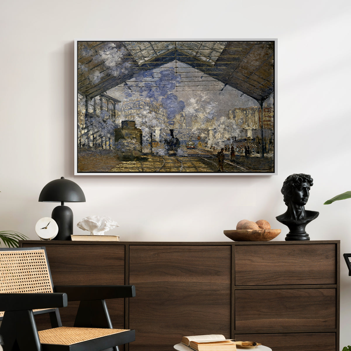 The Gare Saint-Lazare, 1877 by Claude Monet displayed in a white floater framed canvas above a dark wood credenza in an entryway.