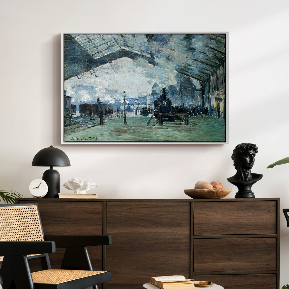 The Saint-Lazare Station, 1877 by Claude Monet displayed in a white floater framed canvas above a dark wood credenza in an entryway.