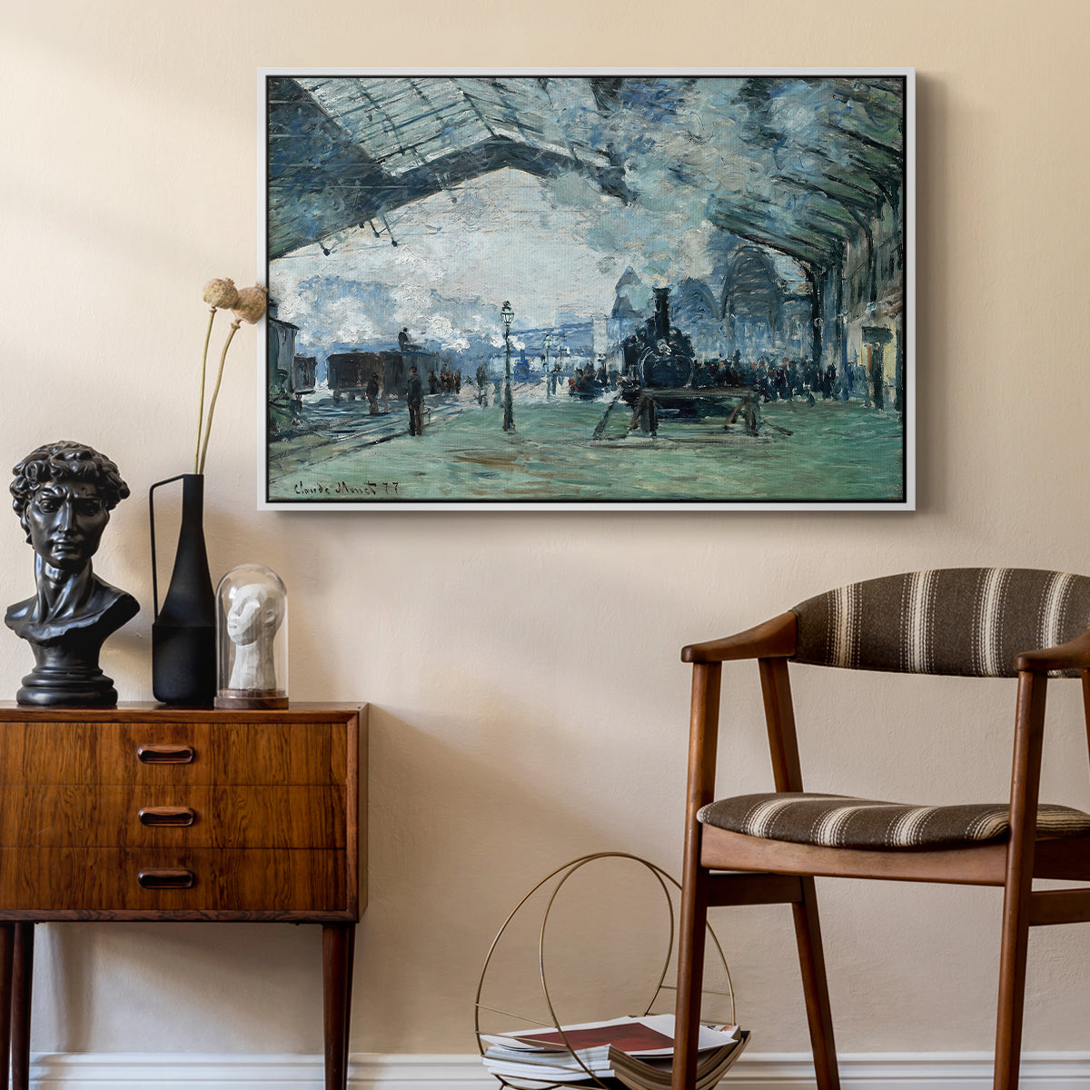 The Saint-Lazare Station, 1877 by Claude Monet as a white floater framed canvas featuring an interior view of station filled with movement and smoke, styled above a mid-century console in a contemporary living area.