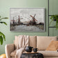 White floater framed canvas featuring a landscape featuring windmills and low horizon sky, displayed above a sofa in a modern living room.