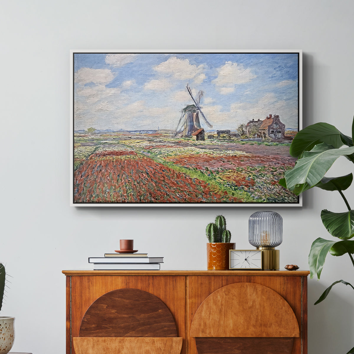 Tulip Fields with the Rijnsburg Windmill, 1886 by Claude Monet in a white floater framed canvas featuring colorful rows of tulip fields leading toward distant windmill, displayed above a wood console cabinet.