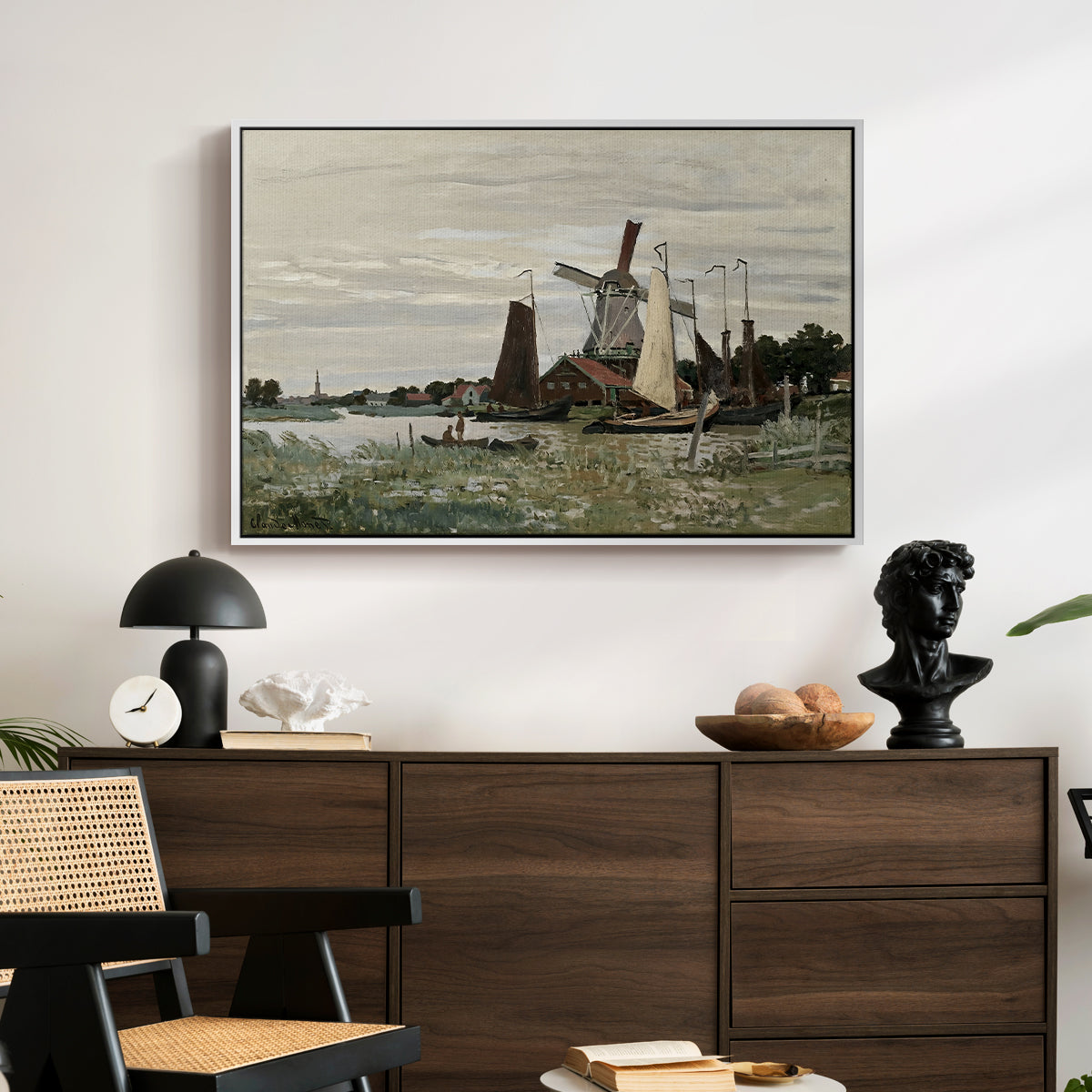 Windmill at Zaandam, 1871 by Claude Monet displayed in a white floater framed canvas above a dark wood credenza in an entryway.