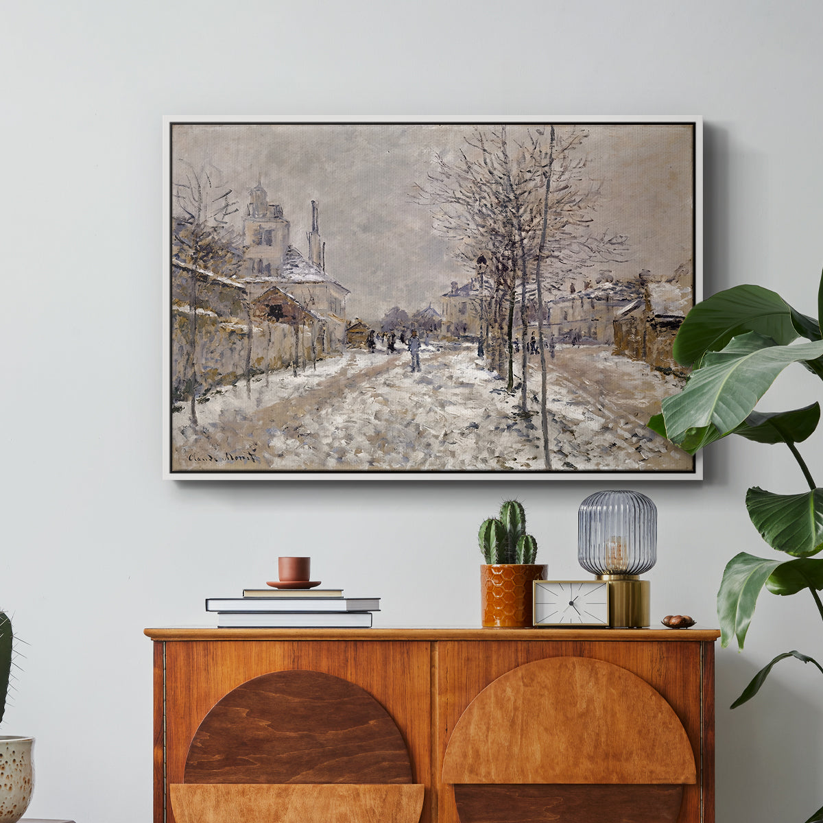 The Boulevard de Pontoise at Argenteuil, Snow Effect, 1875 by Claude Monet in a white floater framed canvas featuring a snow-covered street lined with trees and buildings under winter sky, displayed above a wood console cabinet.