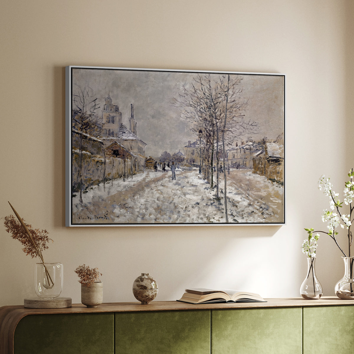 White floater framed canvas of The Boulevard de Pontoise at Argenteuil, Snow Effect, 1875 by Claude Monet, featuring an impressionist winter scene with road and bare trees above a sideboard in a softly lit hallway.