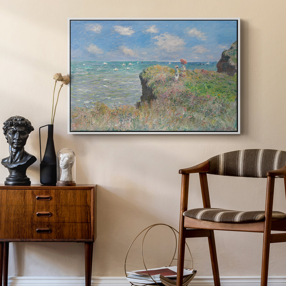 The Cliff Walk at Pourville, 1882 by Claude Monet as a white floater framed canvas featuring a coastal cliff scene with grass, wind, and expansive sea view, styled above a mid-century console in a contemporary living area.