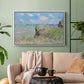 White floater framed canvas featuring an elevated shoreline path with figures and bright sky, displayed above a sofa in a modern living room.