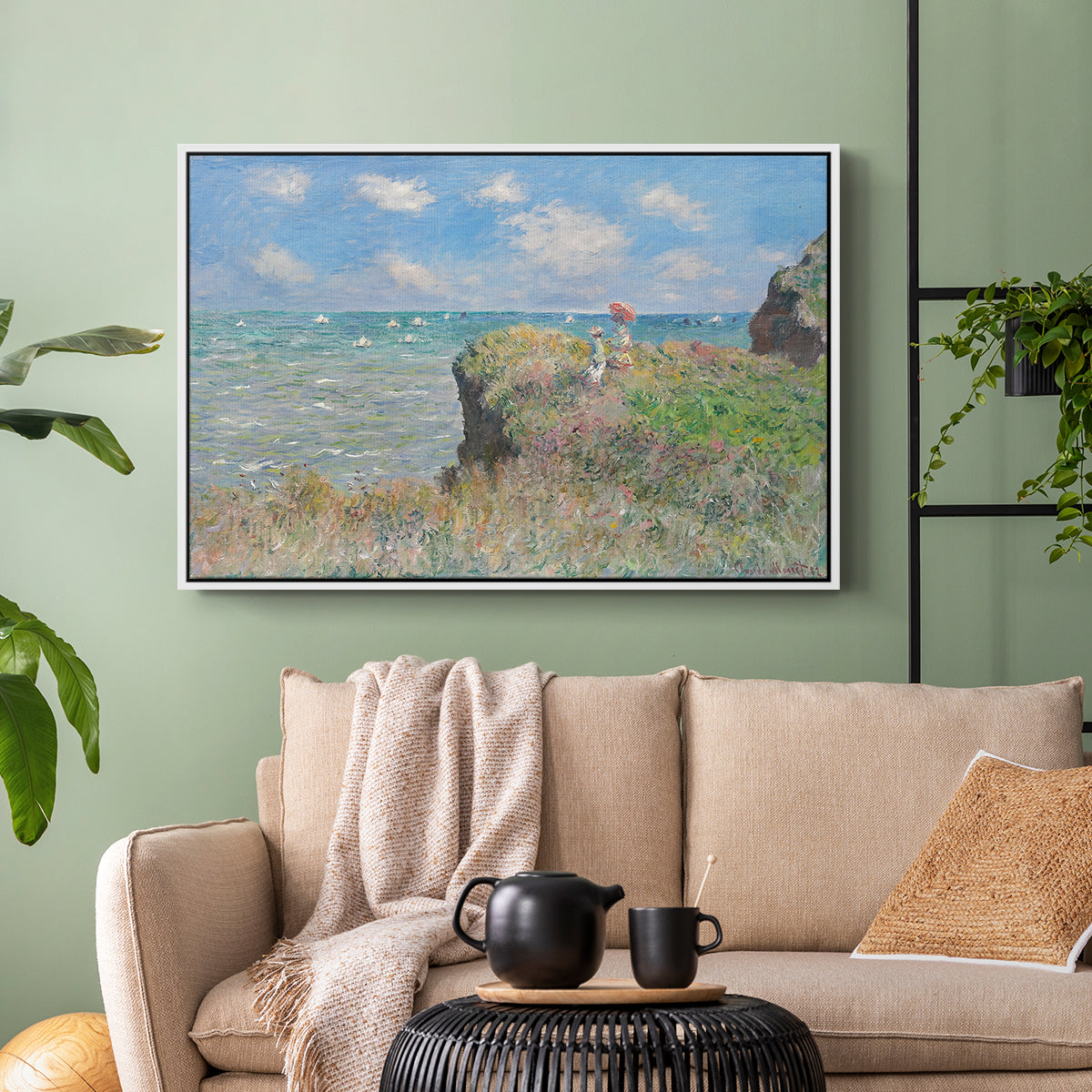 White floater framed canvas featuring an elevated shoreline path with figures and bright sky, displayed above a sofa in a modern living room.