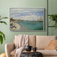 White floater framed canvas featuring a nautical scene with boats racing near seaside town, displayed above a sofa in a modern living room.