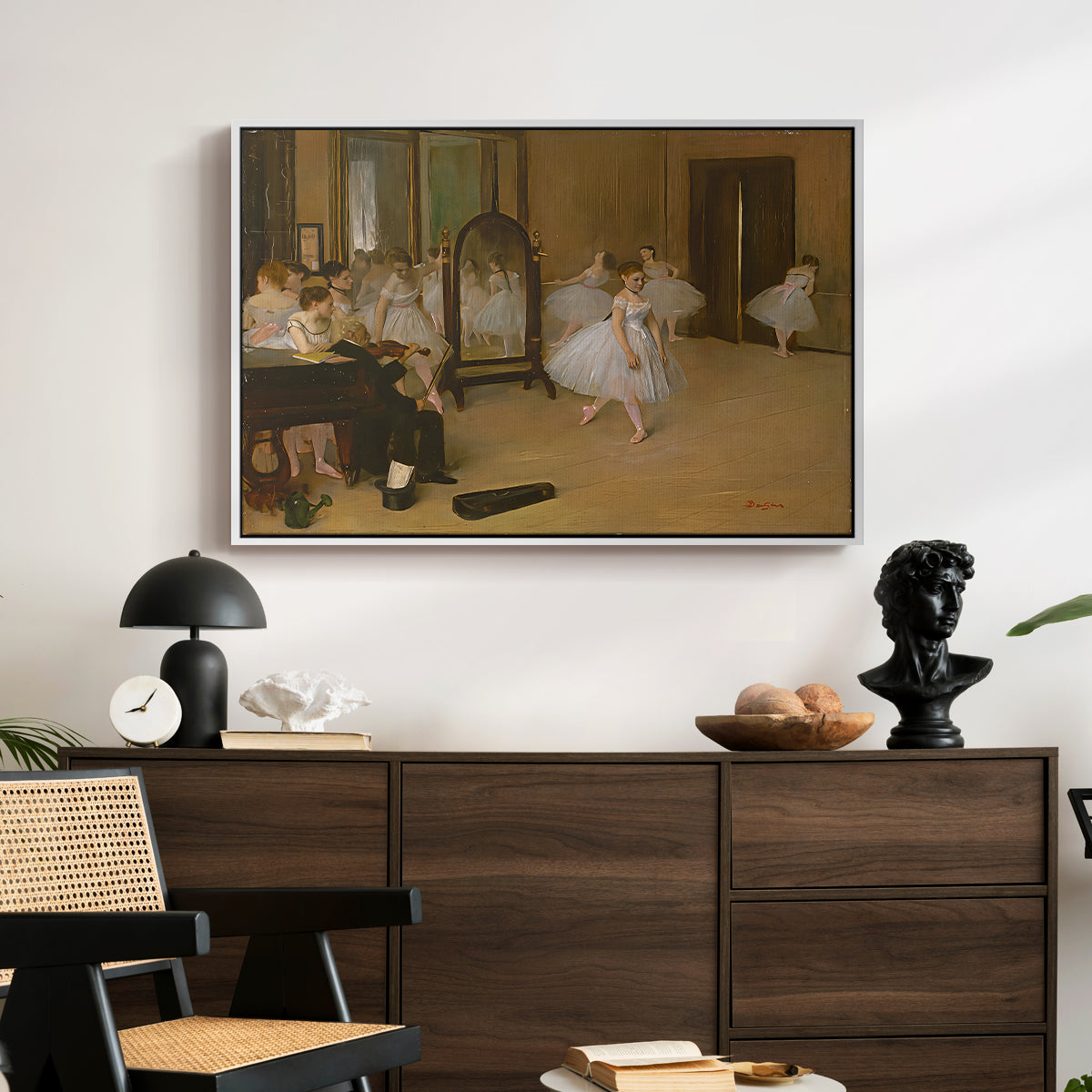 The Dancing Class, c. 1870 by Edgar Degas displayed in a white floater framed canvas above a dark wood credenza in an entryway.