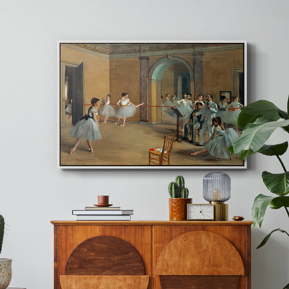 The Dance Foyer at the Opera on the Rue Le Peletier, 1872 by Edgar Degas in a white floater framed canvas featuring ballet dancers gathered in rehearsal hall with mirrors and columns, displayed above a wood console cabinet.