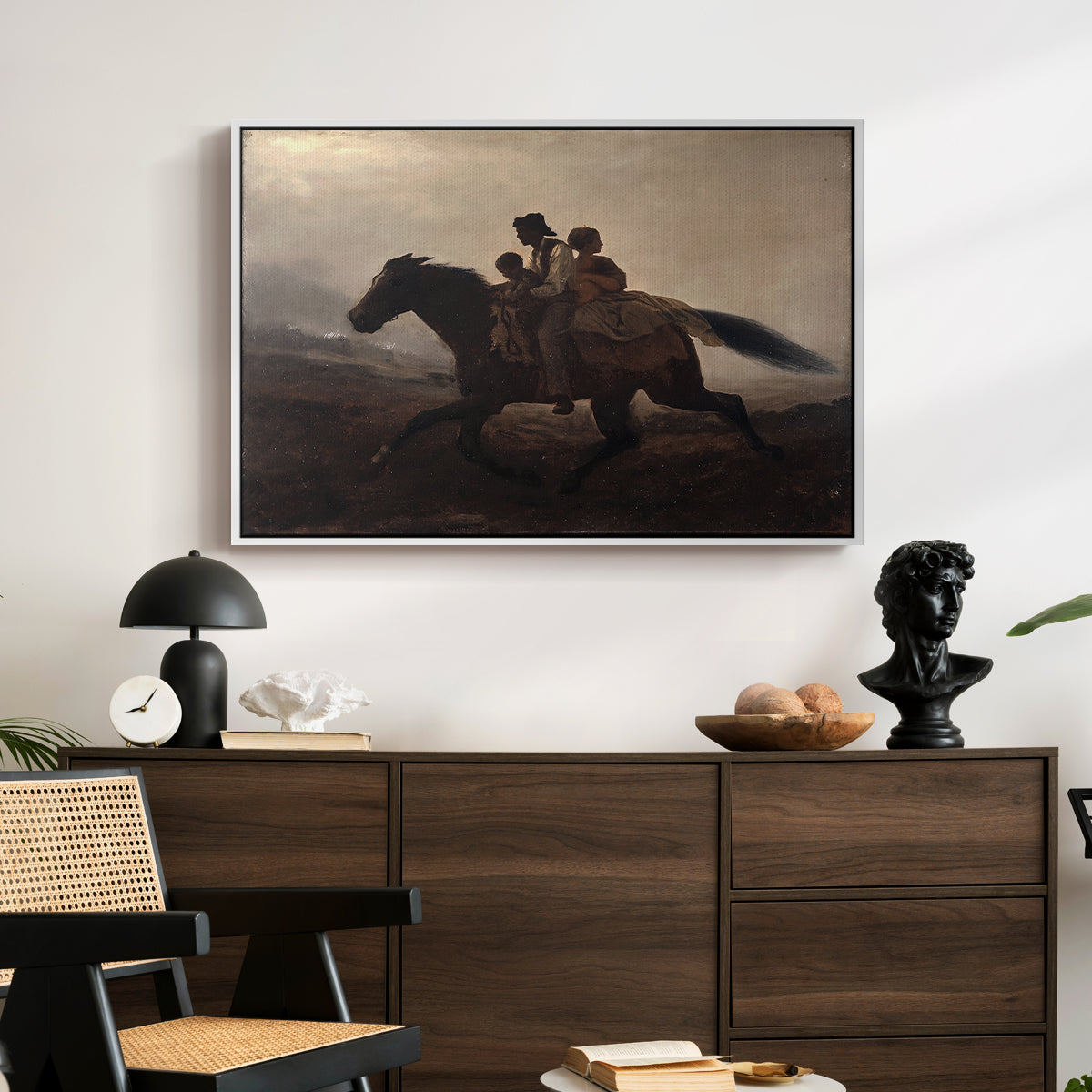 A Ride for Liberty – The Fugitive Slaves, c. 1862 by Eastman Johnson displayed in a white floater framed canvas above a dark wood credenza in an entryway.