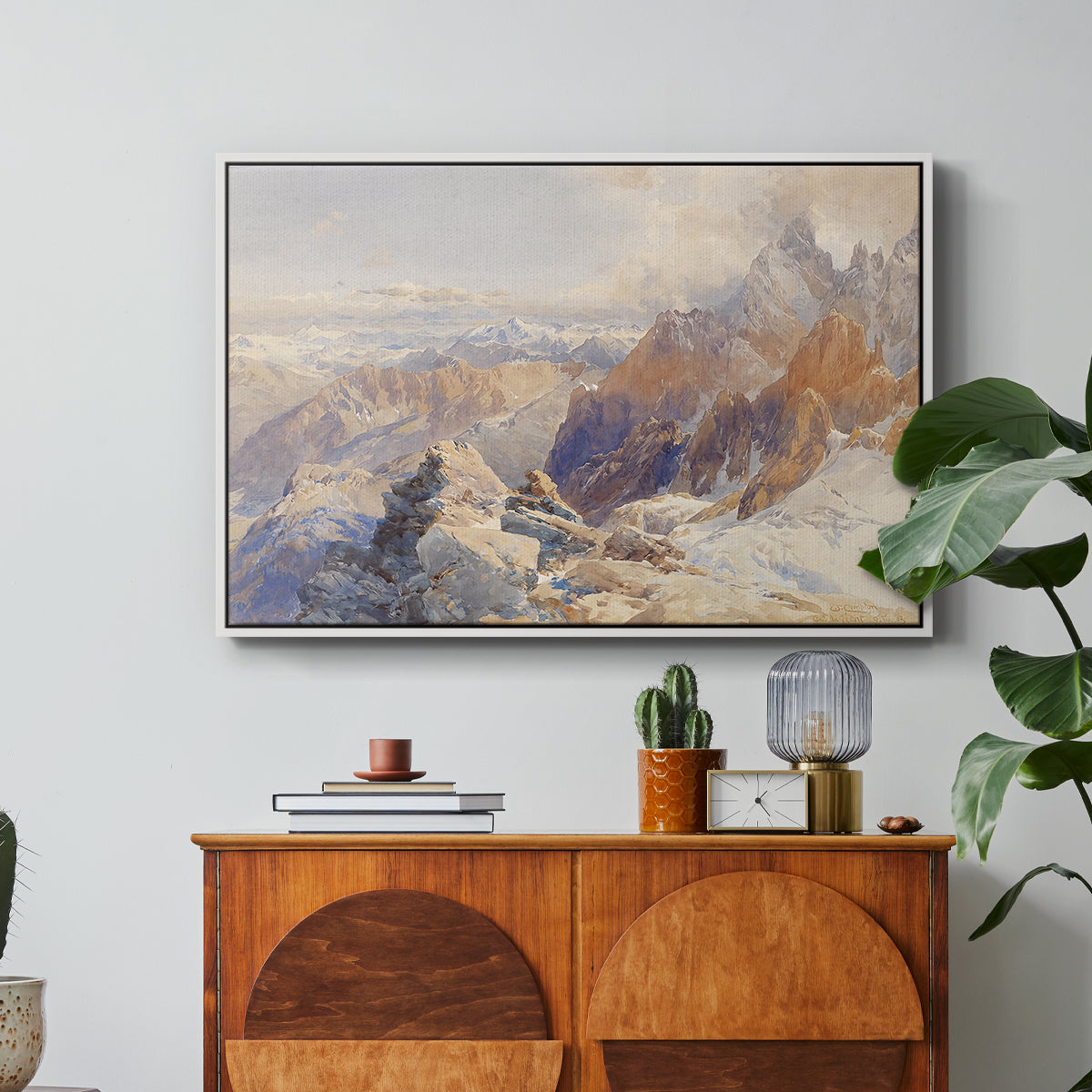 Col du Géant, 1903 by Edward Theodore Compton in a white floater framed canvas featuring a mountain pass with snow-covered peaks and expansive alpine valley, displayed above a wood console cabinet.