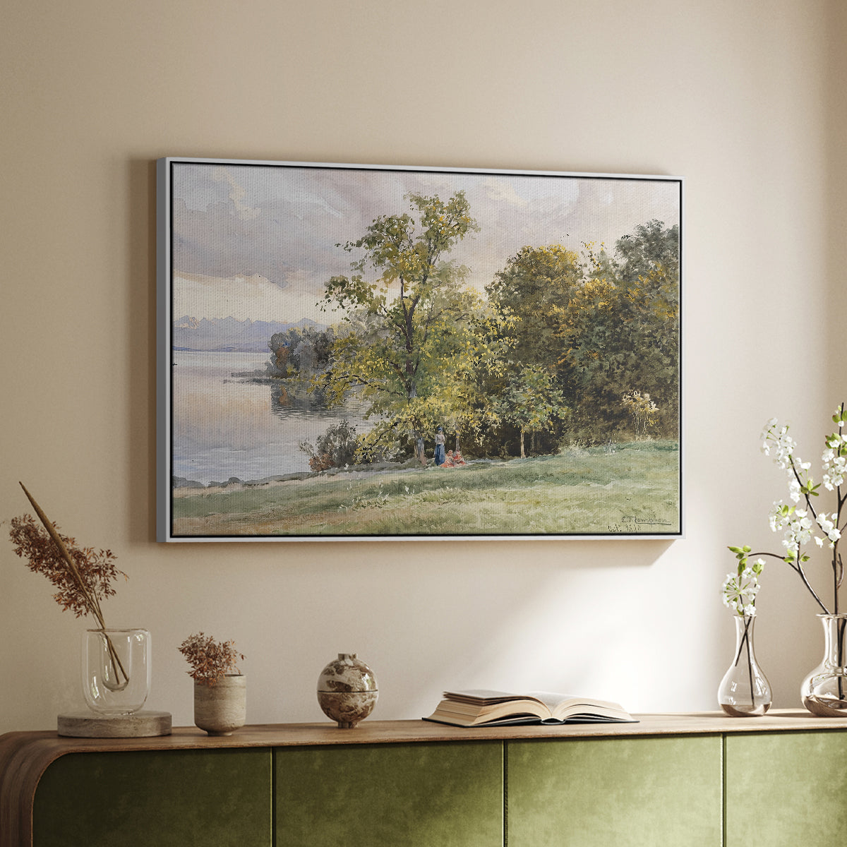 White floater framed canvas of Landscape at Lake Starnberg, 1890 by Edward Theodore Compton, featuring a peaceful lake scene with reflections and surrounding greenery above a sideboard in a softly lit hallway.