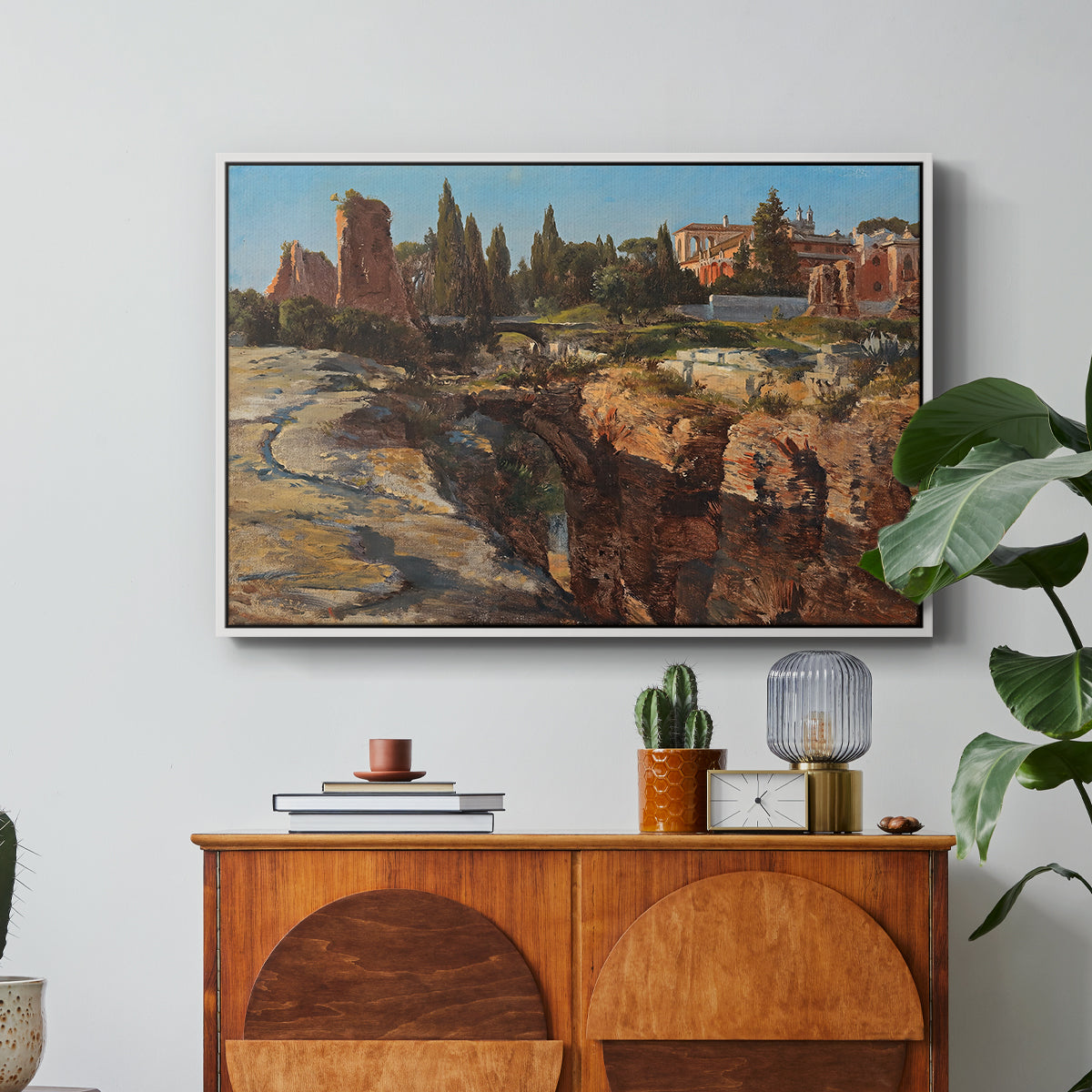 Palatine in Rome, c. 1921 by Edward Theodore Compton in a white floater framed canvas featuring historic Roman ruins and buildings set within warm landscape, displayed above a wood console cabinet.