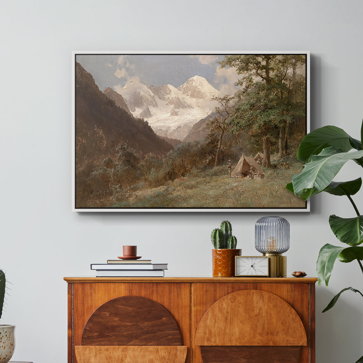 Landscape in the Caucasus, c. 1921 by Edward Theodore Compton in a white floater framed canvas featuring a mountainous landscape with rugged terrain and distant peaks, displayed above a wood console cabinet.