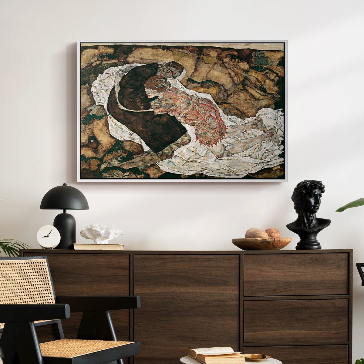 Death and the Maiden, 1915 by Egon Schiele displayed in a white floater framed canvas above a dark wood credenza in an entryway.