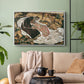 White floater framed canvas featuring an intense composition exploring life and death through figures, displayed above a sofa in a modern living room.