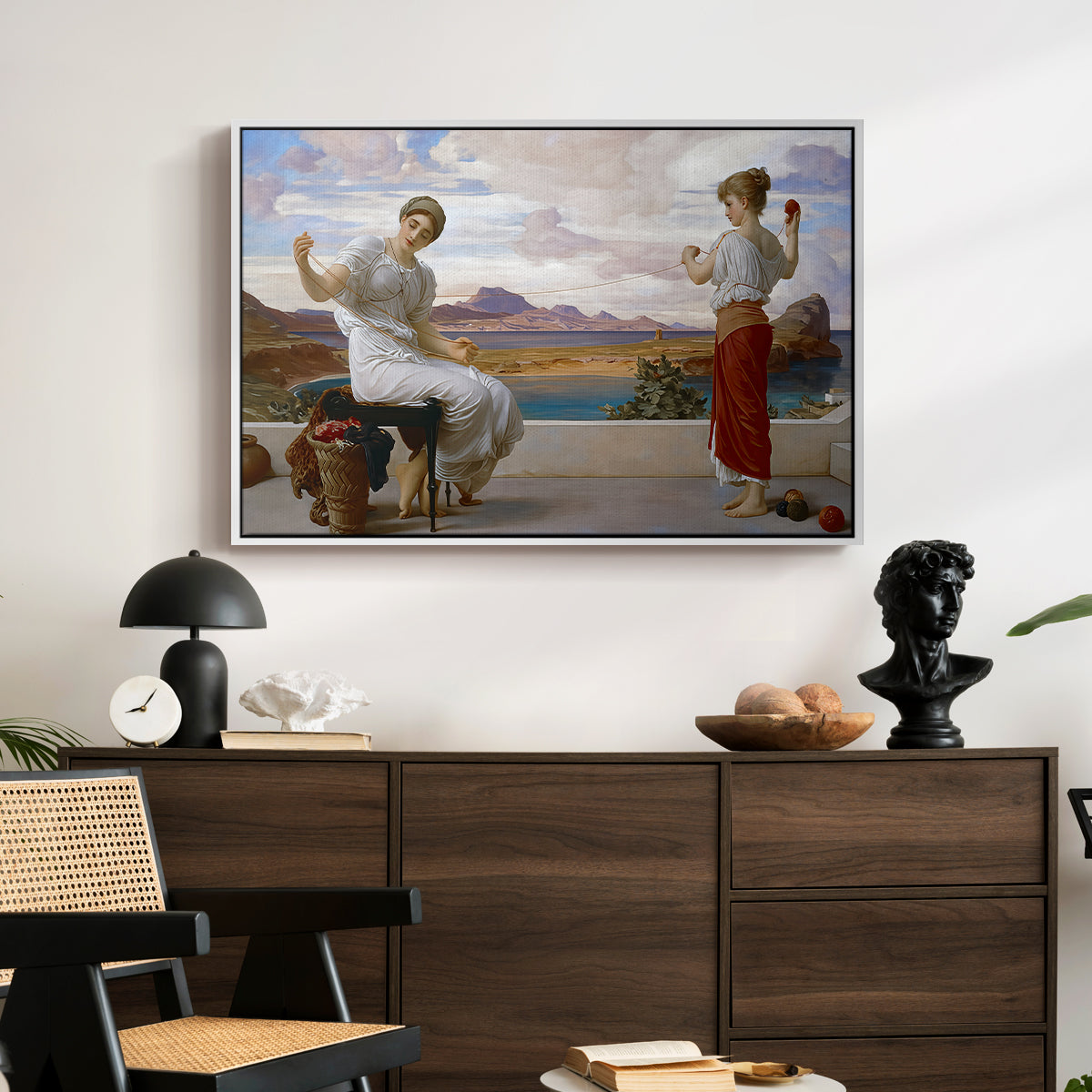 Winding the Skein, c. 1878 by Frederic Leighton displayed in a white floater framed canvas above a dark wood credenza in an entryway.