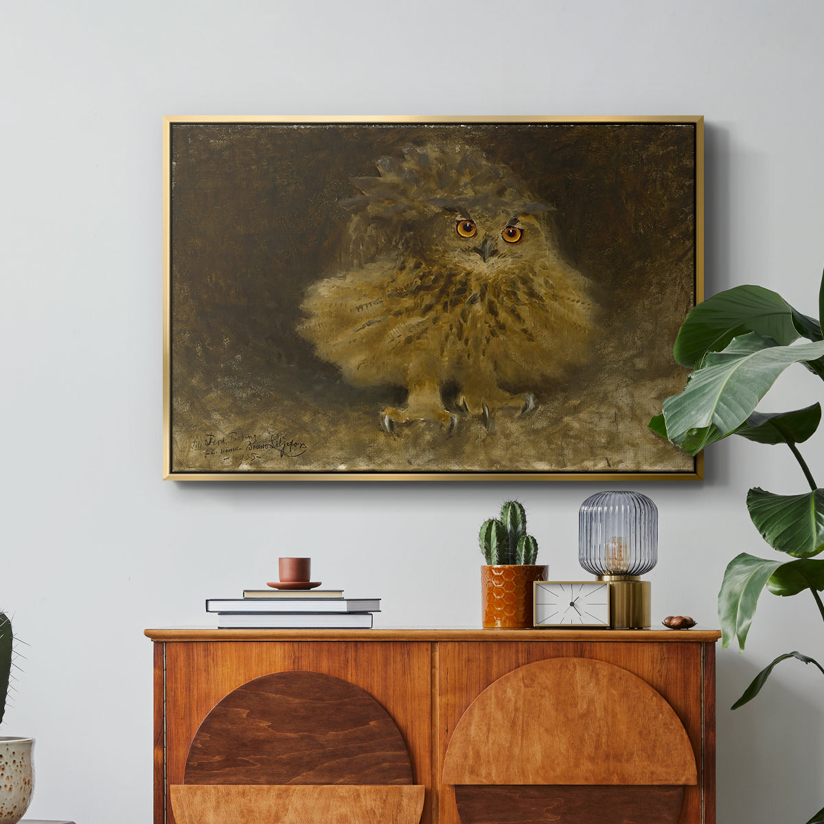 An Eagle Owl (Berguv), 1905 by Bruno Liljefors in a gold floater framed canvas featuring a large owl perched on branch in shadowy natural forest setting, displayed above a wood console cabinet.