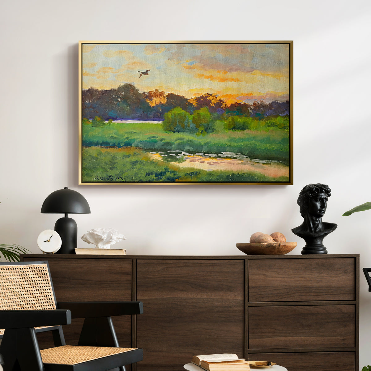 Flying Duck at Sunset, 1924 by Bruno Liljefors displayed in a gold floater framed canvas above a dark wood credenza in an entryway.