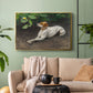 Gold floater framed canvas featuring a calm scene of dog reclining in open landscape, displayed above a sofa in a modern living room.