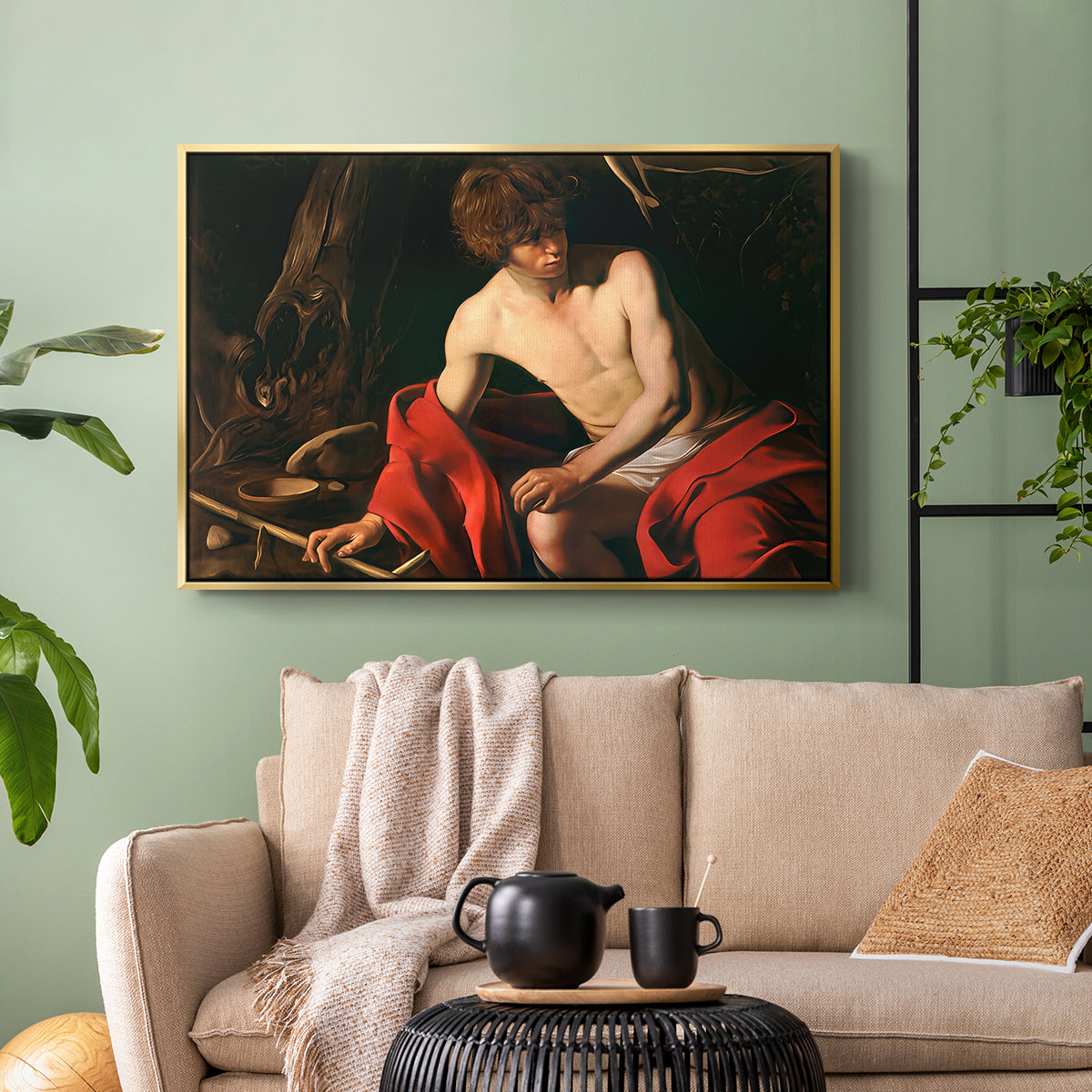 Gold floater framed canvas featuring a contemplative religious figure in rustic wilderness environment, displayed above a sofa in a modern living room.