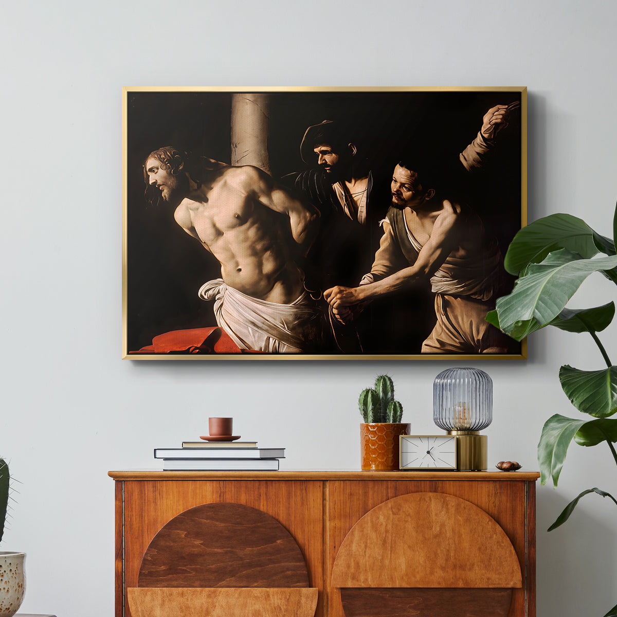The Flagellation of Christ at the Column (Rouen Version), 1606 by Caravaggio in a gold floater framed canvas featuring Christ bound to column while being whipped by surrounding figures, displayed above a wood console cabinet.