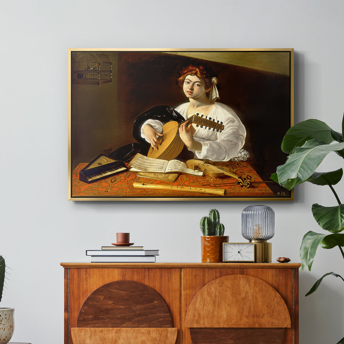 The Lute Player (Wildenstein Version), c. 1596 by Caravaggio in a gold floater framed canvas featuring a young man playing lute surrounded by sheet music and still life objects, displayed above a wood console cabinet.