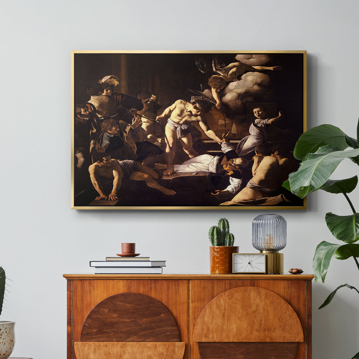 The Martyrdom of Saint Matthew, 1599-1600 by Caravaggio in a gold floater framed canvas featuring a chaotic scene of Saint Matthew being attacked by executioner in church, displayed above a wood console cabinet.