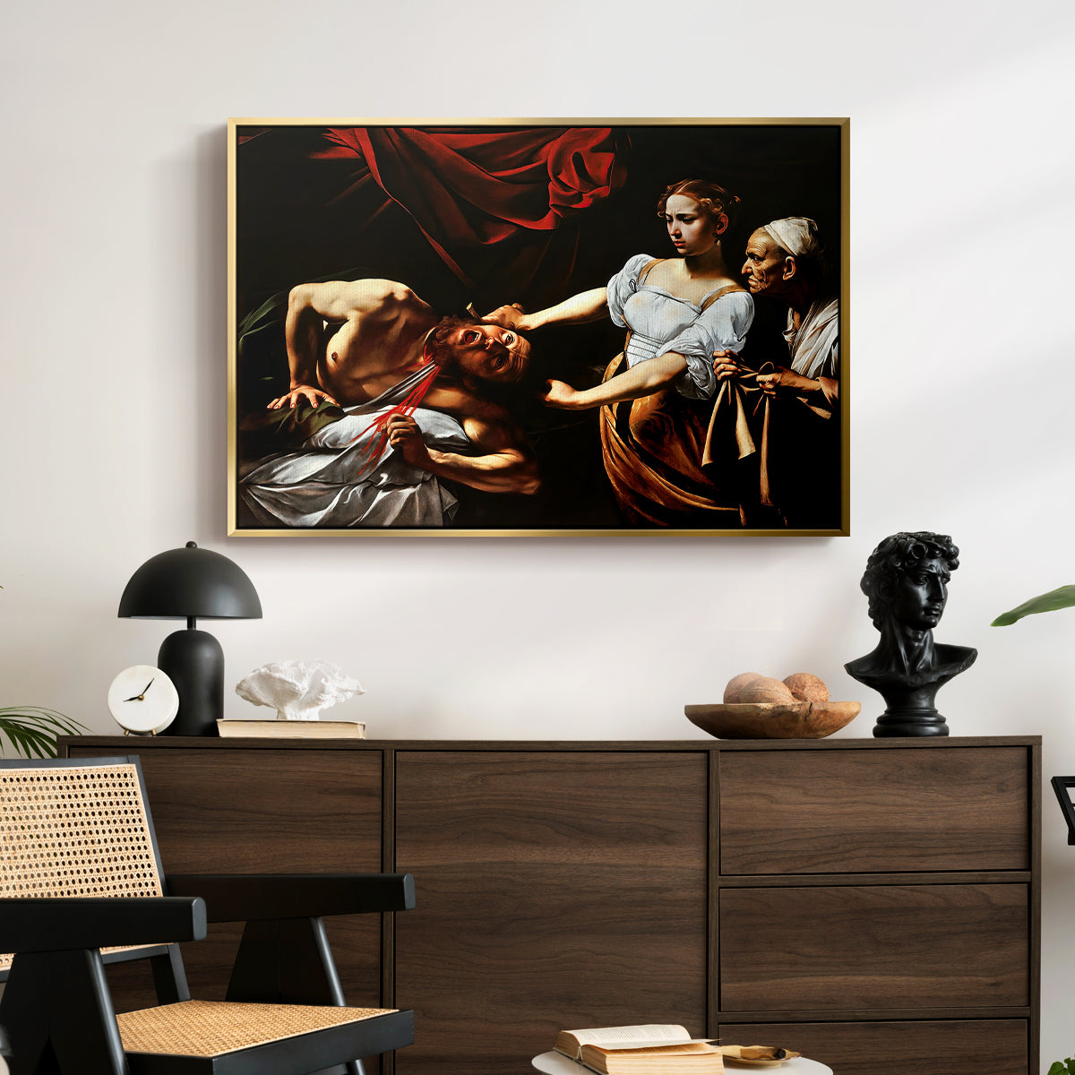 Judith Beheading Holofernes, c. 1599 by Caravaggio displayed in a gold floater framed canvas above a dark wood credenza in an entryway.