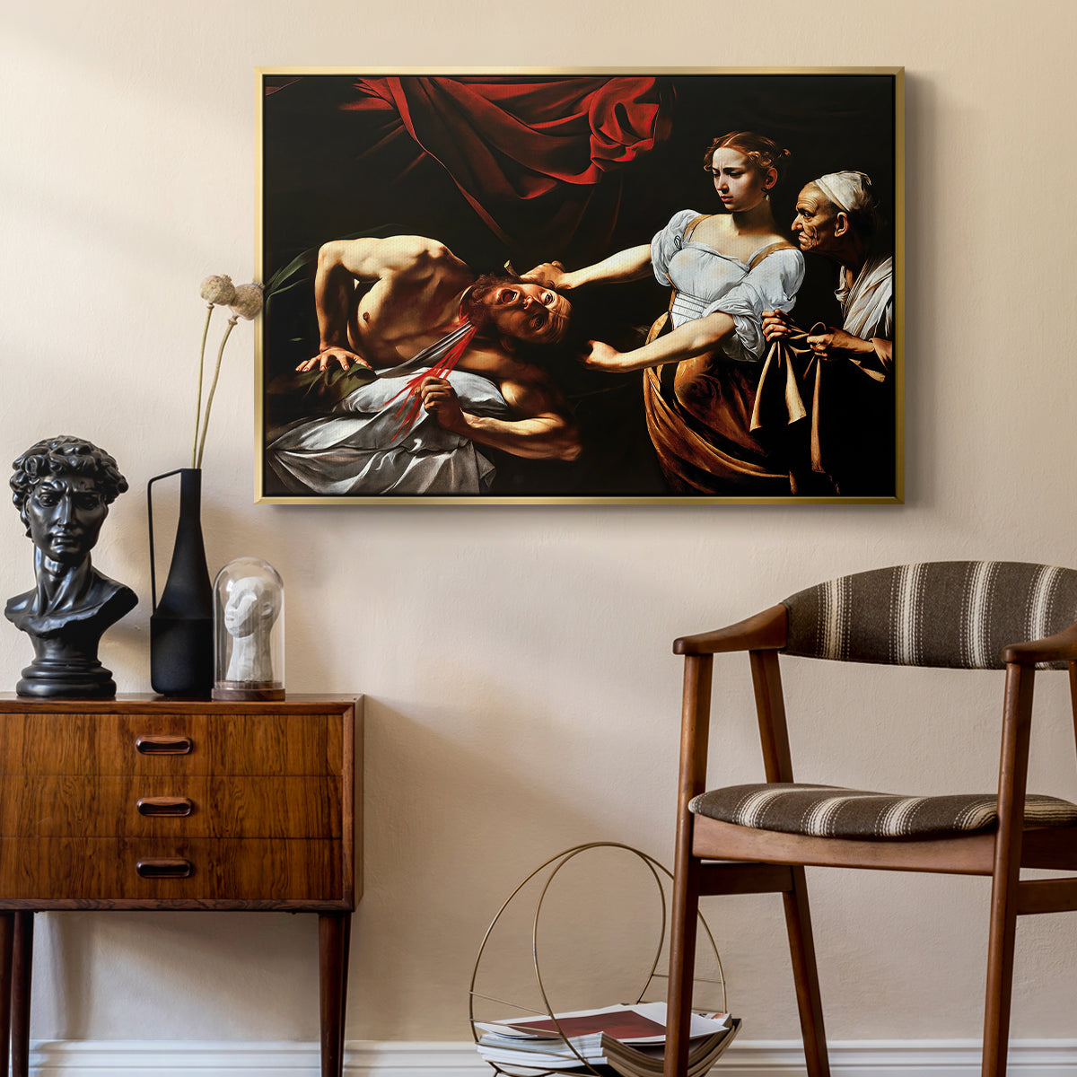 Judith Beheading Holofernes, c. 1599 by Caravaggio as a gold floater framed canvas featuring an intense moment of Judith slaying Holofernes with sword, styled above a mid-century console in a contemporary living area.