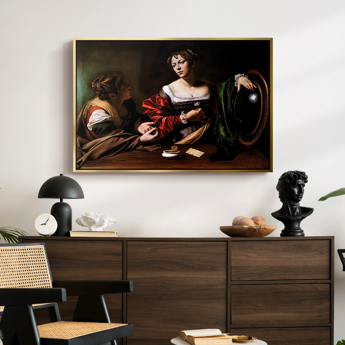 Martha and Mary Magdalene, c. 1598 by Caravaggio displayed in a gold floater framed canvas above a dark wood credenza in an entryway.