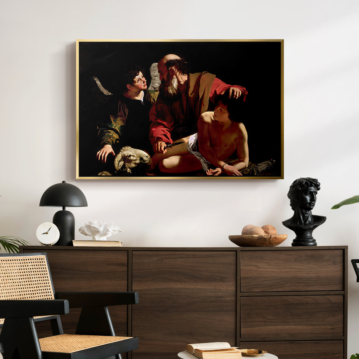 The Sacrifice of Isaac (Uffizi Version), c. 1603 by Caravaggio displayed in a gold floater framed canvas above a dark wood credenza in an entryway.