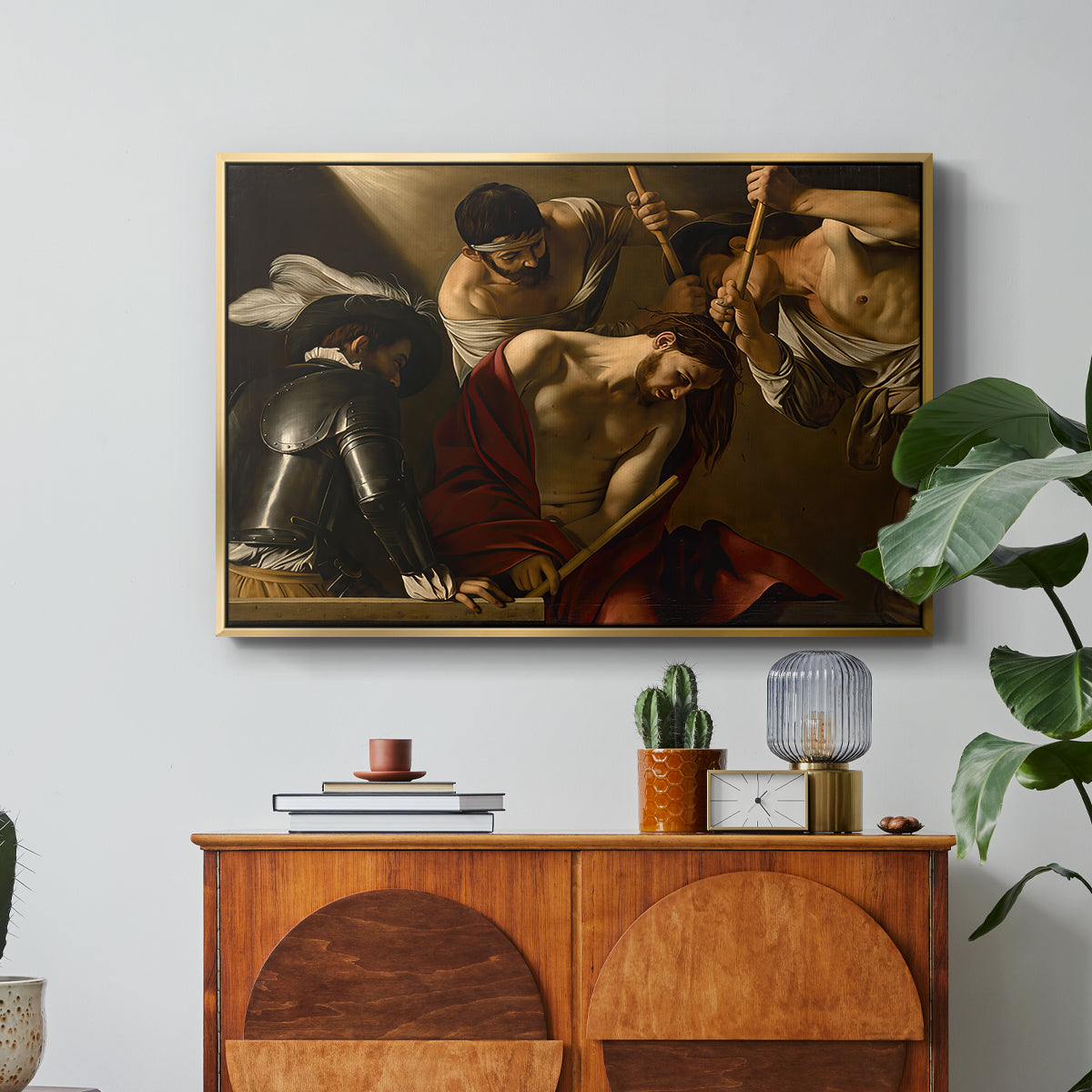 The Crowning with Thorns (Vienna Version), c. 1602-1604 by Caravaggio in a gold floater framed canvas featuring Christ surrounded by men pressing crown of thorns onto his head, displayed above a wood console cabinet.
