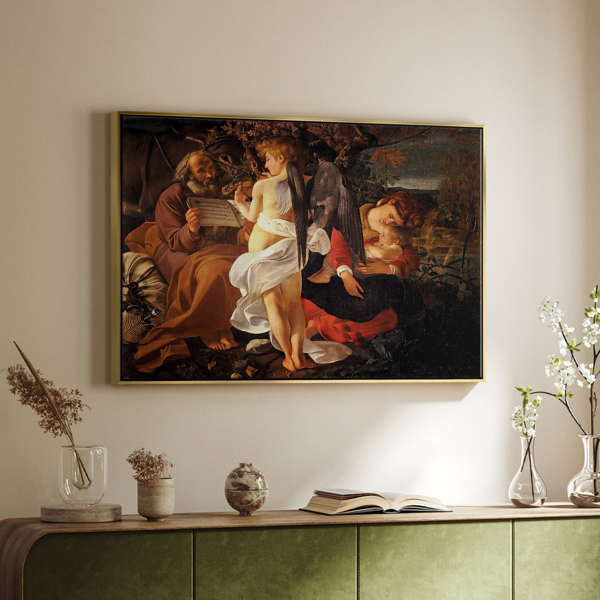 Gold floater framed canvas of Rest on the Flight into Egypt, c. 1597 by Caravaggio, featuring a biblical scene of Mary, Joseph, and infant resting with angel musician above a sideboard in a softly lit hallway.