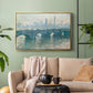 Gold floater framed canvas featuring an atmospheric urban landscape with misty light and reflections, displayed above a sofa in a modern living room.