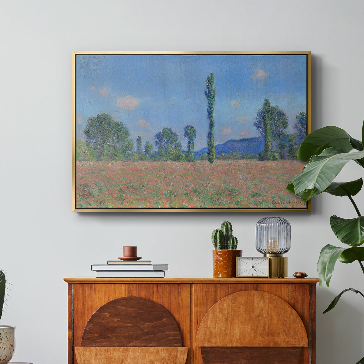 Poppy Field (Giverny), 1890-1891 by Claude Monet in a gold floater framed canvas featuring an expansive field of red poppies with tall trees under blue sky, displayed above a wood console cabinet.