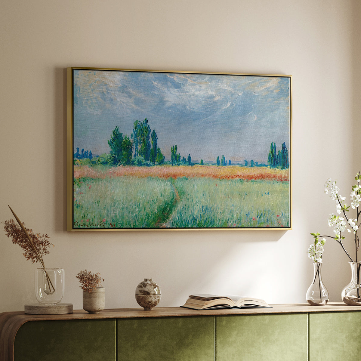 Gold floater framed canvas of The Wheat Field (Champ de Blé), 1881 by Claude Monet, featuring an impressionist depiction of ripened grain field in countryside above a sideboard in a softly lit hallway.
