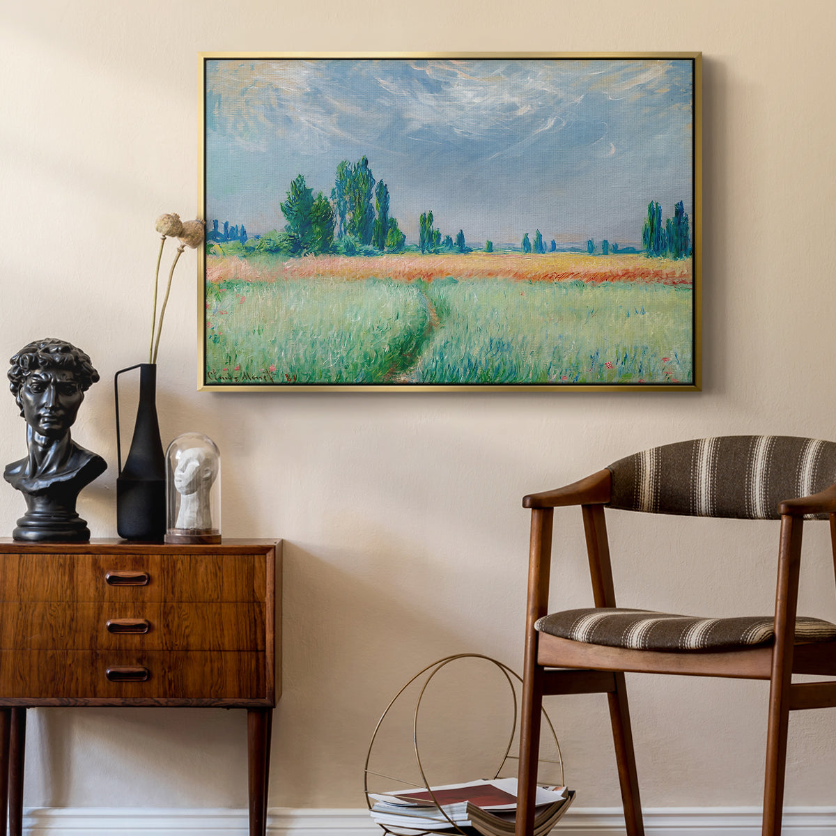The Wheat Field (Champ de Blé), 1881 by Claude Monet as a gold floater framed canvas featuring an agricultural landscape with tall wheat and distant horizon, styled above a mid-century console in a contemporary living area.